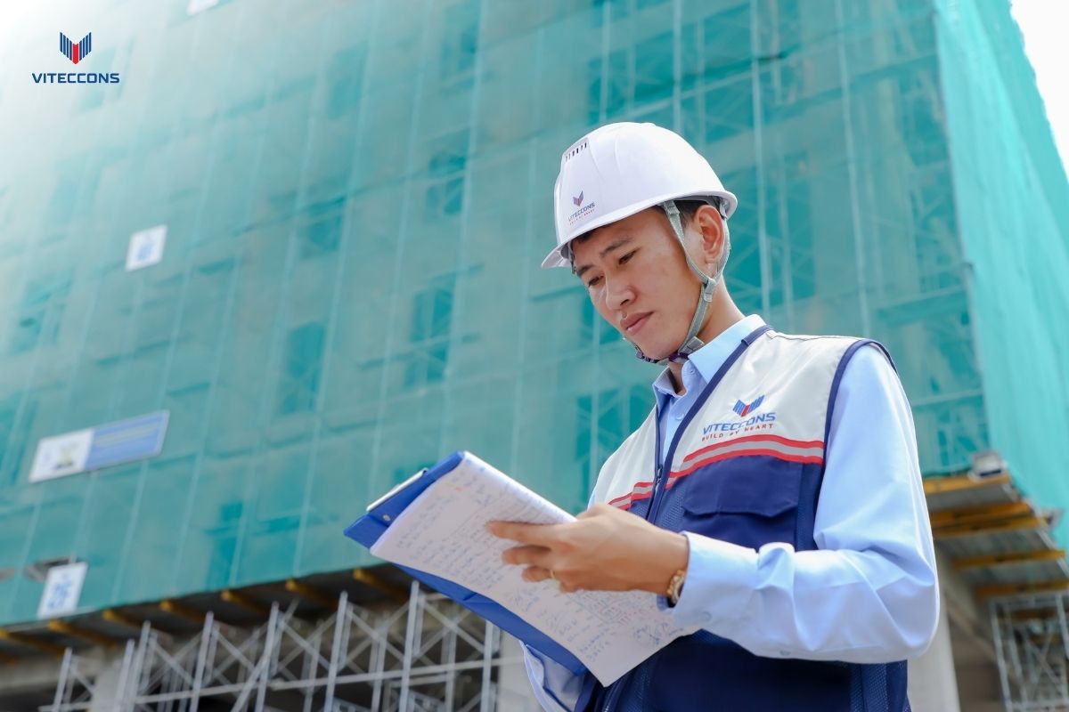 Anh Văn Anh đọc sổ ghi chép trước khối nhà đang thi công
